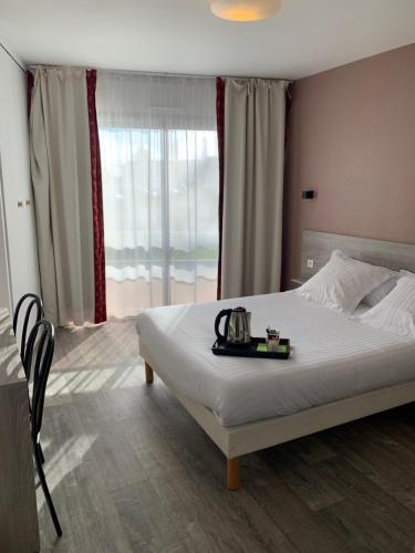 a bedroom with a bed and a large window at Hôtel Au Relais des Lilas in Parthenay