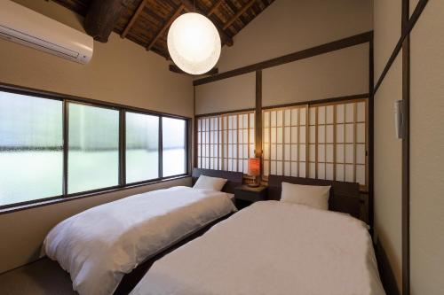 two beds in a room with two windows at Natsume an Machiya House in Kyoto