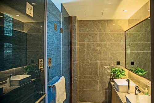 ein Bad mit einer Dusche, einem Waschbecken und einem Spiegel in der Unterkunft Lanmei Boutique Hotel West Station Branch Lanzhou (Lanzhou City Center Branch) in Lanzhou