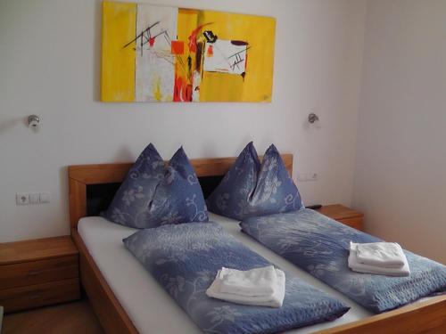 Un dormitorio con una cama con almohadas azules y una pintura en Appartements Jäger, en Flachau