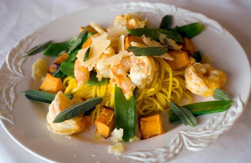 a white plate of pasta with shrimp and vegetables at The Spotted Chook and Amelie's Petite Maison in Montville