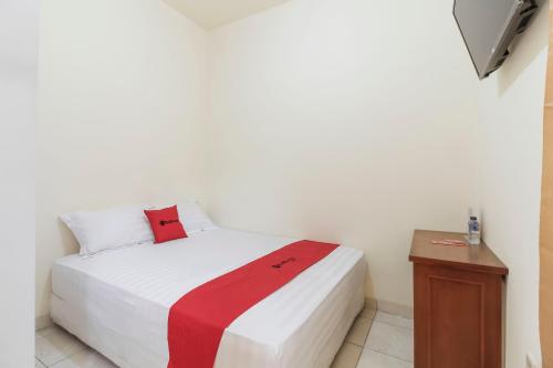 una camera con un letto bianco e una coperta rossa di RedDoorz @ Tanjung Duren a Giacarta