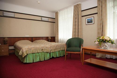 a bedroom with a bed and a chair and a table at Park Hotel Mechta in Oryol