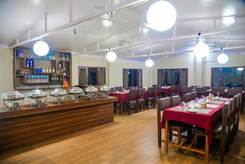 Un restaurante con mesas y sillas y un bar. en Hotel Chitwan Park Village, en Sauraha