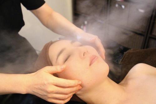 Una mujer que se rocía la cara con vapor en Guest House "Ro"kumano, en Shimonoseki