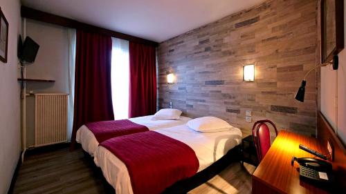 une chambre d'hôtel avec un lit et un mur en briques dans l'établissement Le Vert Galant, à Villepinte