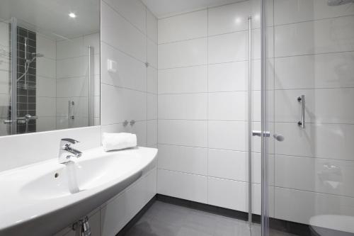 a white bathroom with a sink and a shower at Park Inn by Radisson Oslo Airport Hotel West in Gardermoen