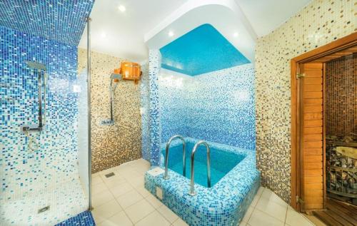 a bathroom with a shower and a blue tiled wall at Albatros Hotel in Anapa