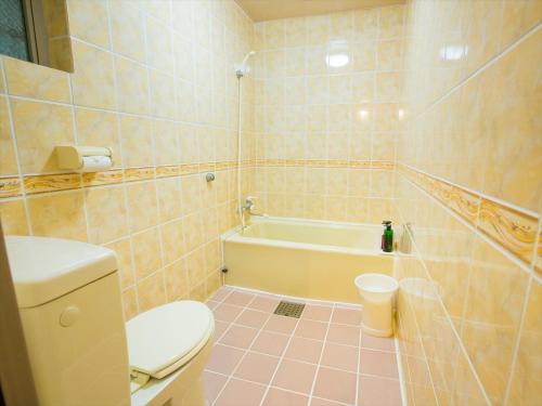 a bathroom with a toilet and a bath tub at Hotel Palm Tree Hill in Okinawa City