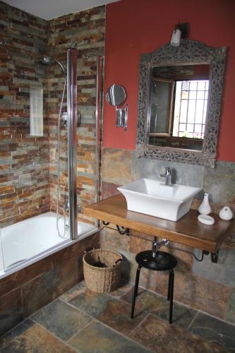 a bathroom with a sink and a tub and a mirror at Casa Rural El Olivar de Valdefuentes in Valdefuentes