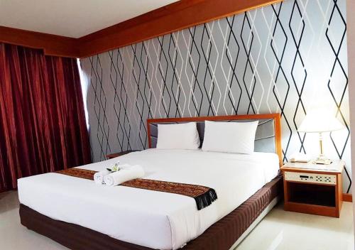 a hotel room with a bed with white sheets at JP Emerald Hotel in Yasothon