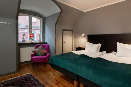 a bedroom with a bed and a purple chair at Victory Apartments in Stockholm