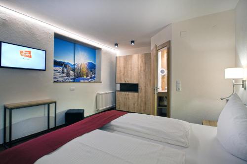 a bedroom with a bed and a tv on the wall at Hotel Truyenhof in Ried im Oberinntal