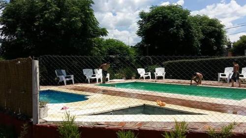 a swimming pool with chairs and a fence at Cabañas Kehuen in Cordoba