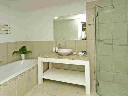 a bathroom with a sink and a tub and a mirror at The Knysna Belle Guest House in Knysna