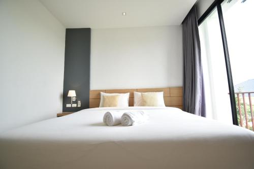 a bedroom with a large white bed with towels on it at B Boutique Residence in Suratthani