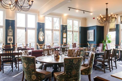 a dining room with tables and chairs and windows at The Cheshire Cat by Innkeeper's Collection in Chester