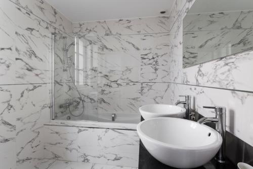 uma casa de banho branca com um lavatório e um espelho em Din'Art by Cocoonr em Dinard