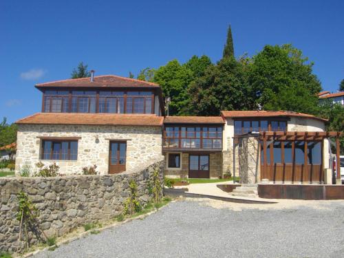 a large house with a stone wall and a fence at O Canto da Terra in Pantón