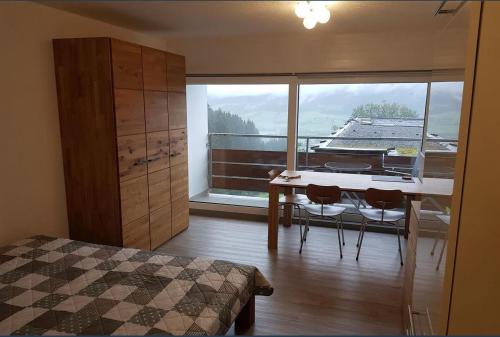 1 dormitorio con mesa, sillas y ventana grande en Berghof Appartement Top 22, en Ellmau