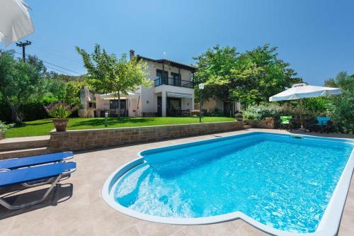 a swimming pool with two chairs and an umbrella at Villa Helios in Pefkochori