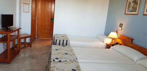 a room with two beds and a television in it at Hotel Torre De Los Guzmanes in La Algaba