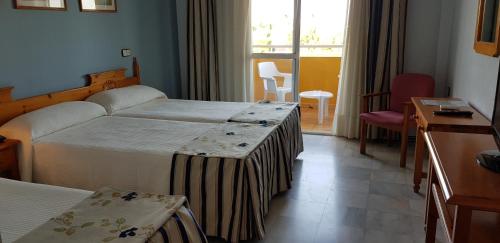 a hotel room with two beds and a window at Hotel Torre De Los Guzmanes in La Algaba