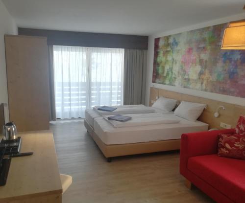 a bedroom with a bed and a red couch at Family Hotel Schloss Rosenegg in Fieberbrunn