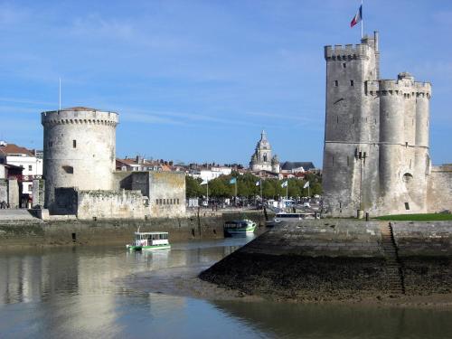 a castle with two towers next to a body of water at Appartement au calme Centre Ville à 2 pas du vieux marché in La Rochelle