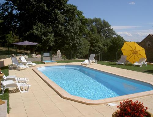 une piscine avec des chaises longues et un parasol dans l'établissement Domaine de Malouziès, à Fontiers-Cabardès