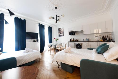 a bedroom with two beds and a kitchen with a table at RESIDENCE MONTORGUEIL in Paris