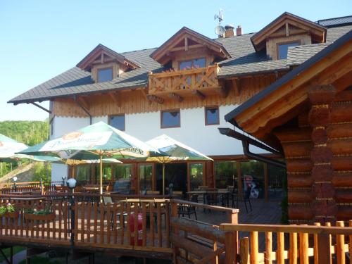 a building with a deck with tables and umbrellas at Rezidence u Jezera in Jeseník