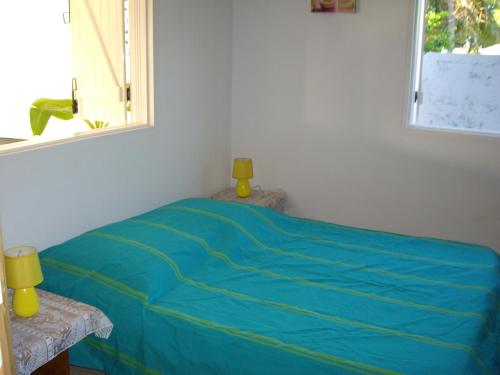 a bedroom with a blue bed with a window at Très belle location touristique in Sainte-Anne