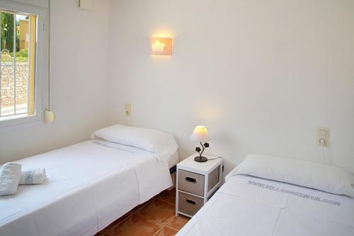 two beds in a white room with a window at Villas Guzman - Apartamento Velazquez in Benitachell