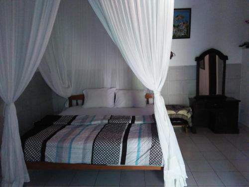 a bedroom with a canopy bed with white curtains at Barclona Guesthouses Lovina in Buleleng