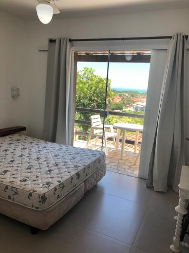 een slaapkamer met een bed en een balkon met uitzicht bij Flat Geribá com linda vista, 500 metros da praia in Búzios