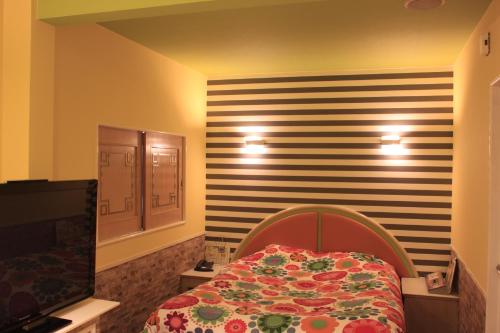 a bedroom with a bed and a striped wall at Hotel Miami (Adult Only) in Metabaru