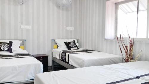 a room with two beds and a window at Sanee Grace in Madikeri