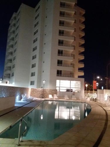 a swimming pool in front of a building at night at Departamento frente al mar in La Serena