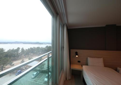 a bedroom with a bed and a large window with a view at Gyeongpo Soo Hotel in Gangneung