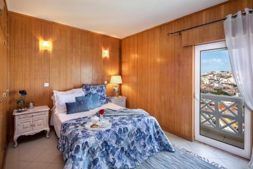 um quarto com uma cama com um cobertor azul e uma janela em Sea View Downtown - Albufeira em Albufeira