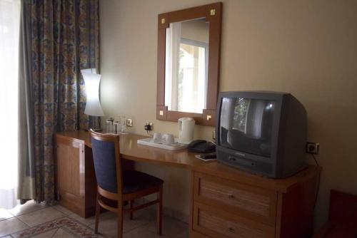 a room with a desk with a tv and a mirror at The Kairaba Beach Hotel in Kololi