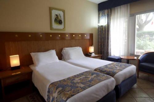 a hotel room with two beds and a window at The Kairaba Beach Hotel in Kololi