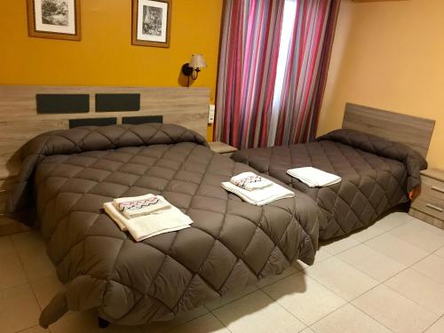 um quarto de hotel com duas camas com toalhas em El Quijote em El Toboso