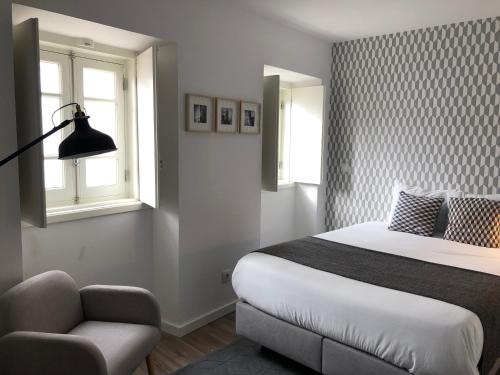 a bedroom with a bed and a chair and a window at São Bento na Alta in Coimbra