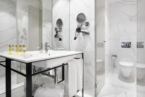 a white bathroom with a sink and a toilet at Eurostars Porto Centro in Porto