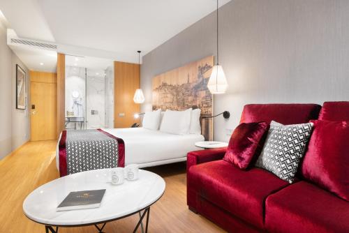 a hotel room with a bed and a red couch at Eurostars Porto Centro in Porto