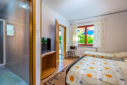 ein Schlafzimmer mit einem Bett, einem Fernseher und einem Fenster in der Unterkunft Garden paradise App in Sveti Vid-Miholjice