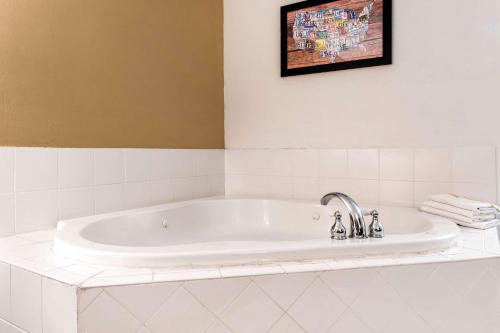 a white bath tub in a white tiled bathroom at Econo Lodge in Holland