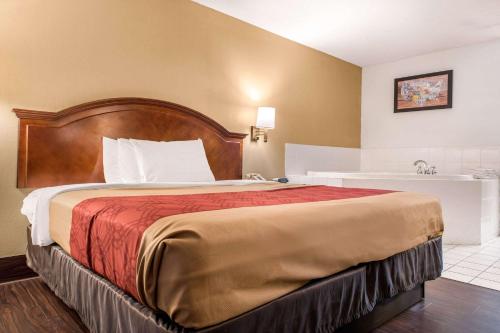a bedroom with a large bed with a wooden headboard at Econo Lodge in Holland